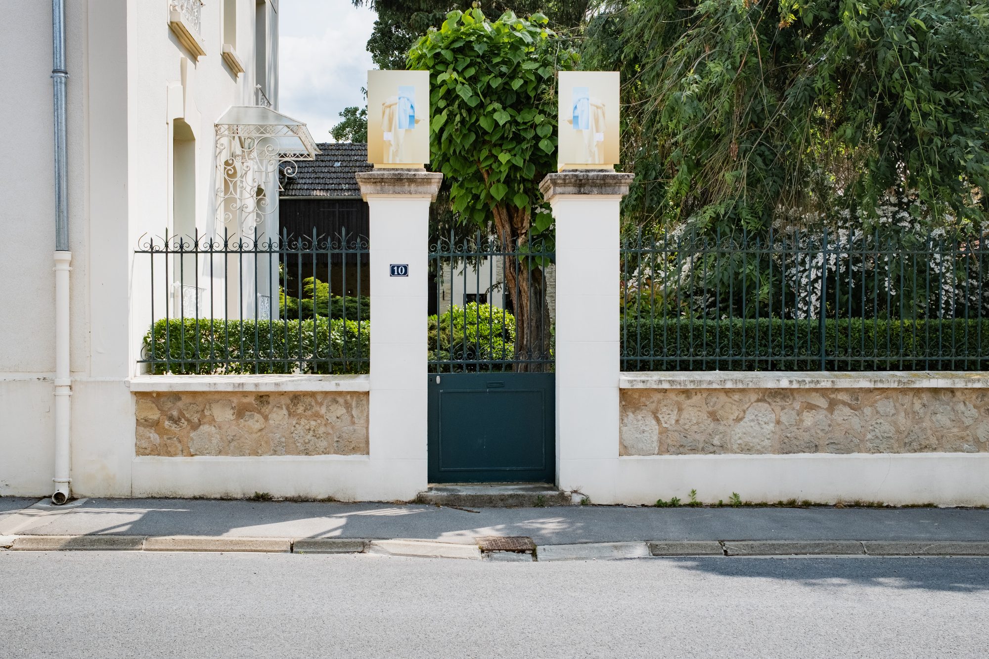 Portail entre deux voitures garées, photographies sur les piliers