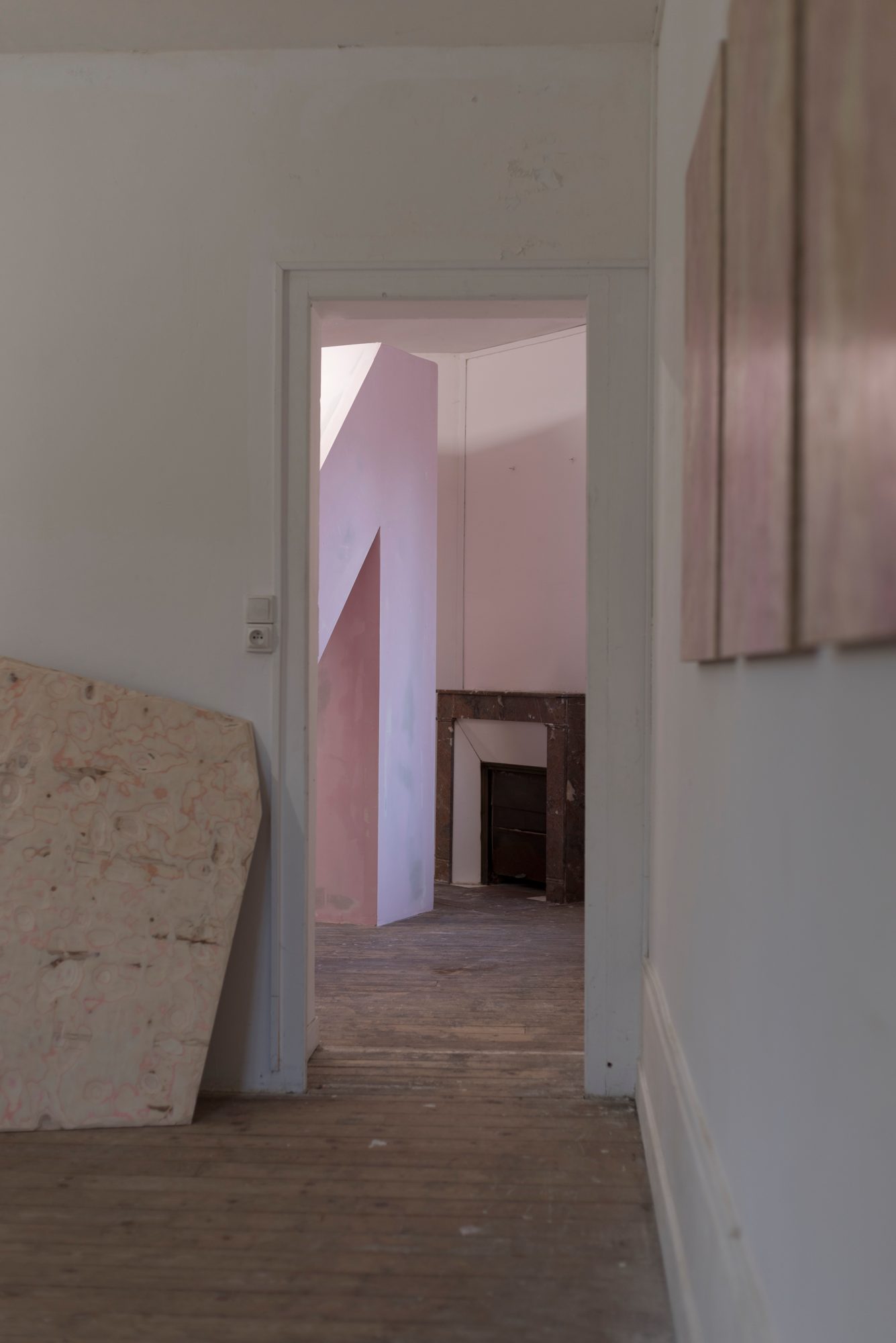 Vue en enfilade d’une porte vers une salle occupée par une structure rose