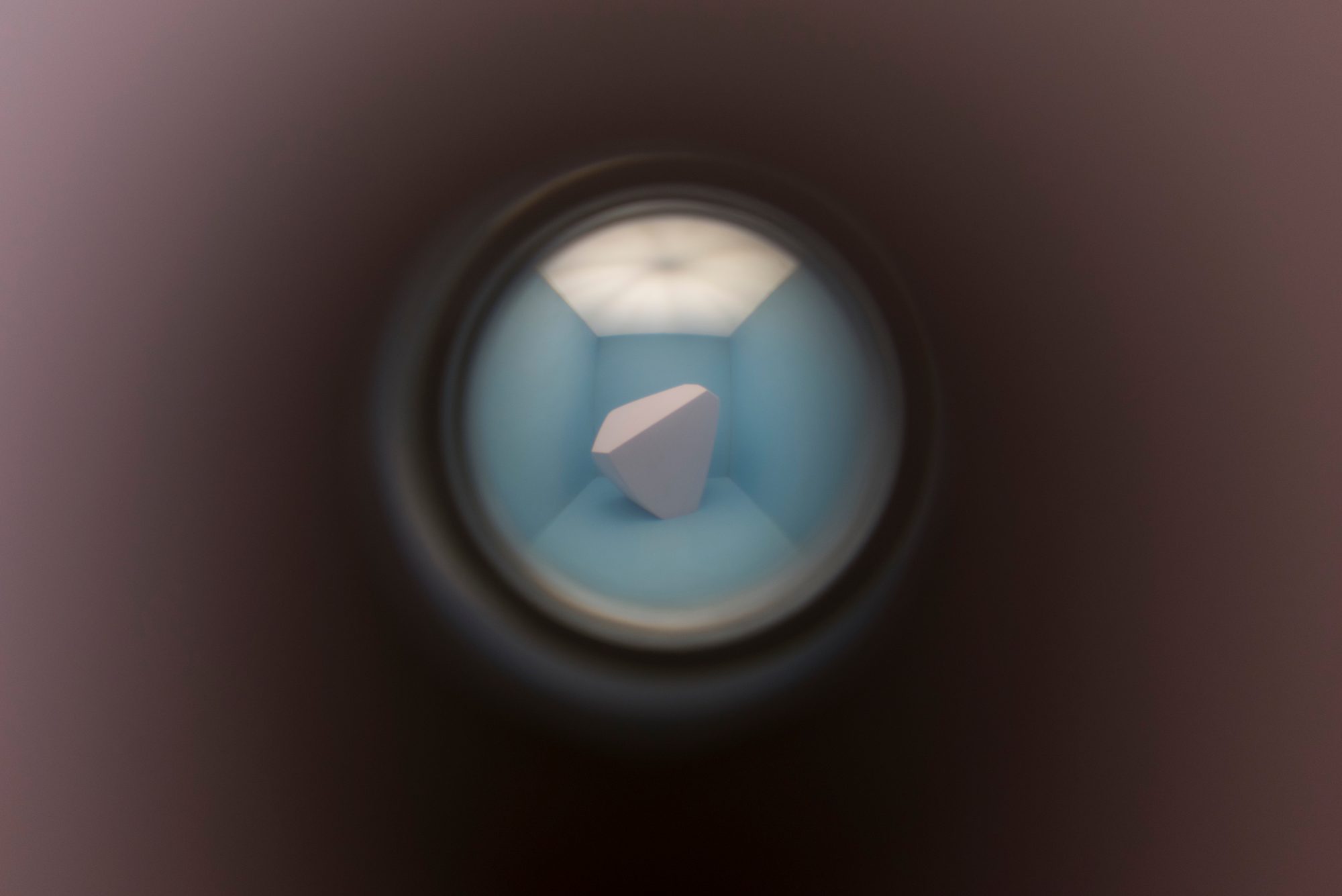 Vue à travers un judas d’un volume blanc dans une boîte bleue