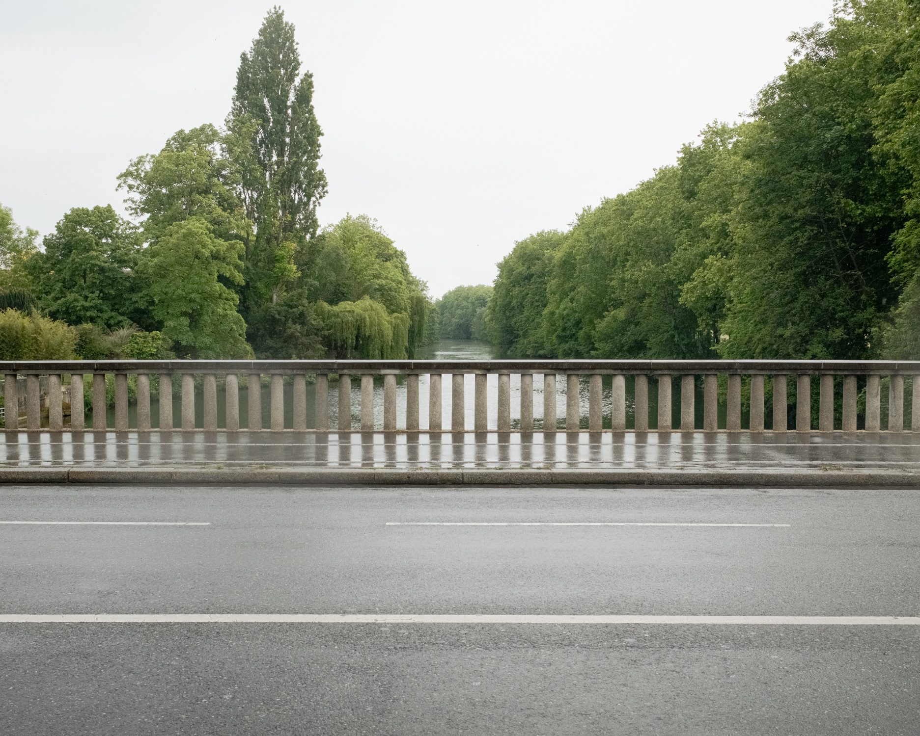 Pont à balustrade au-dessus d’une rivière bordée d’arbres