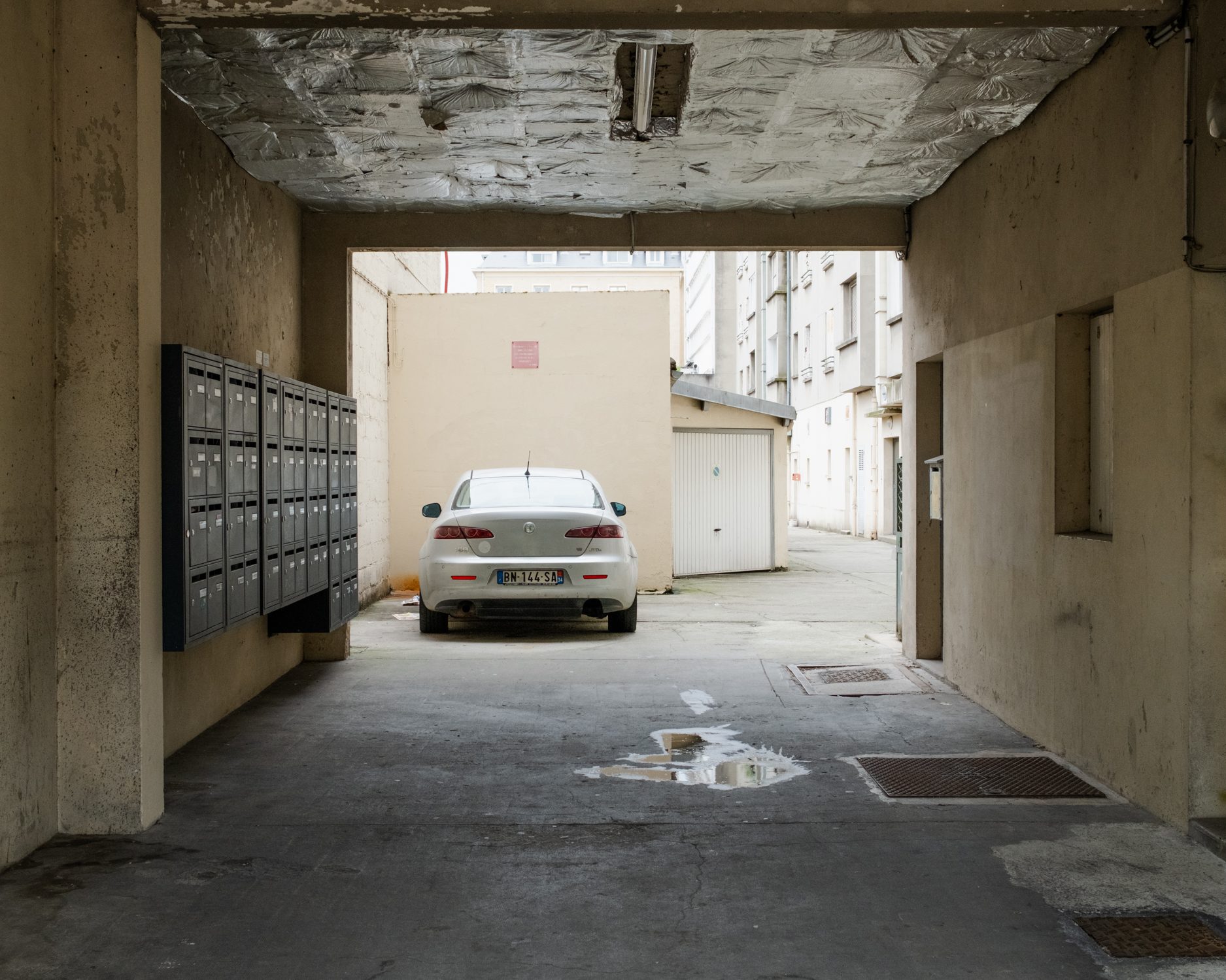 Passage couvert avec boîtes aux lettres et voiture garée