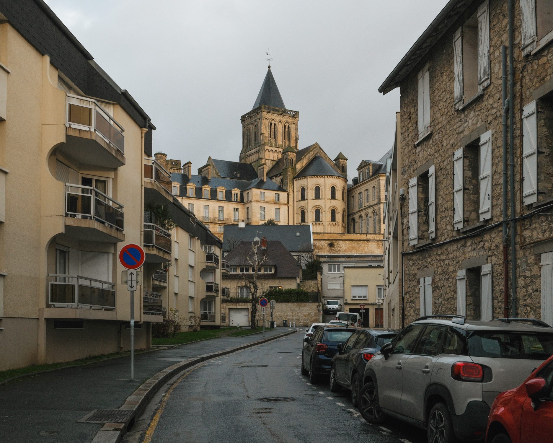 Rue montante vers l’abbaye, voitures garées