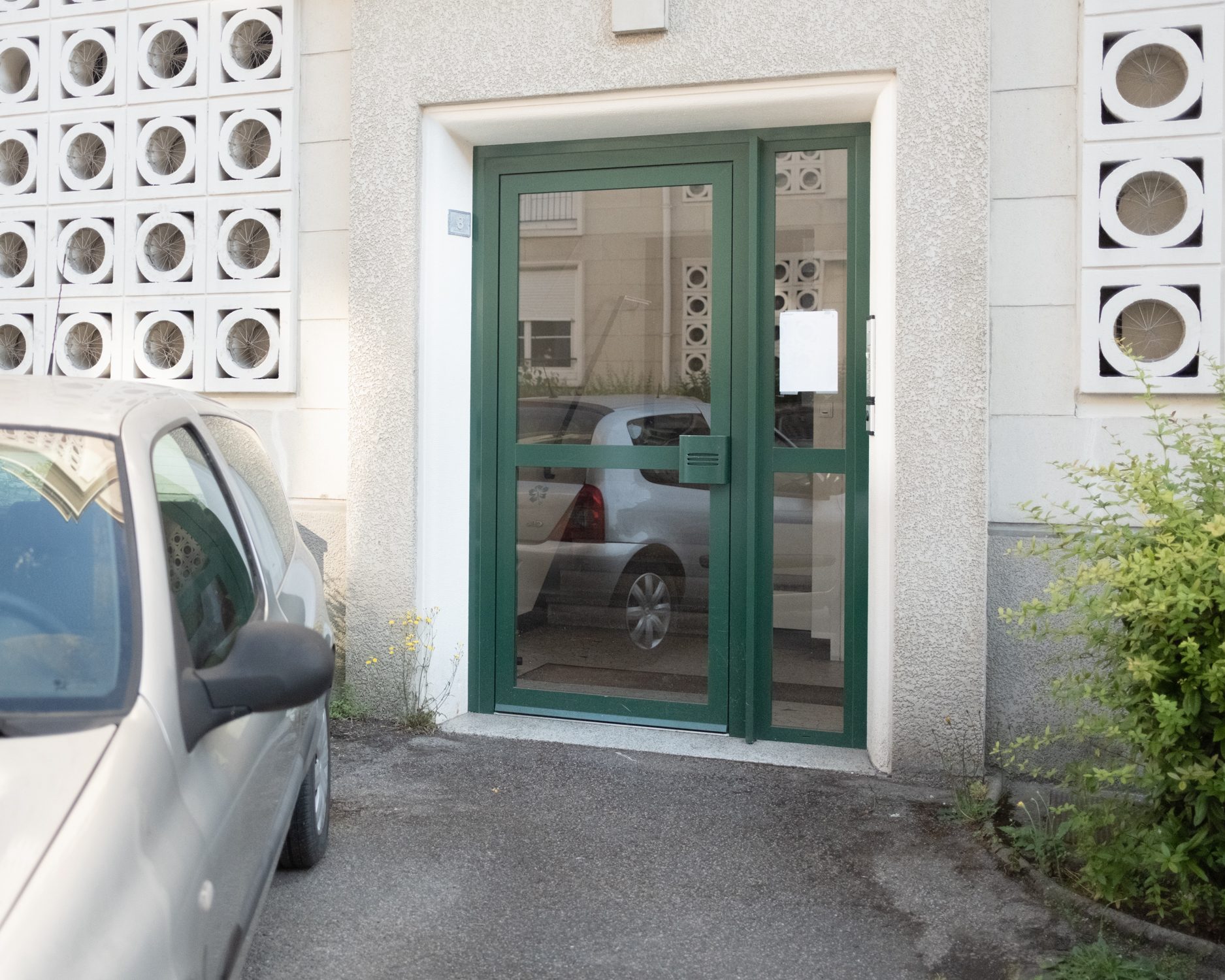 Porte d’entrée verte entre des claustras de béton