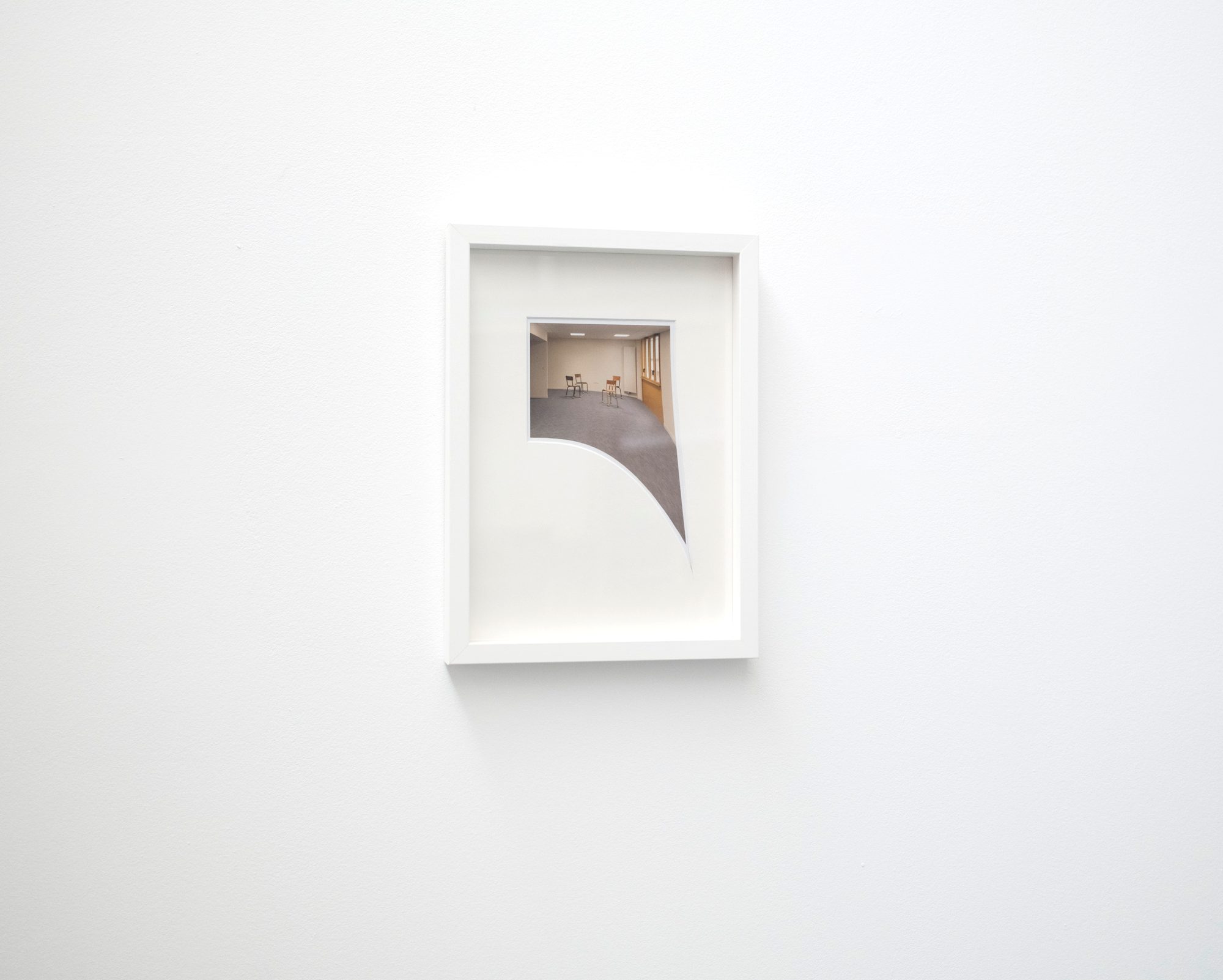 Petit cadre blanc accroché seul sur un mur blanc
